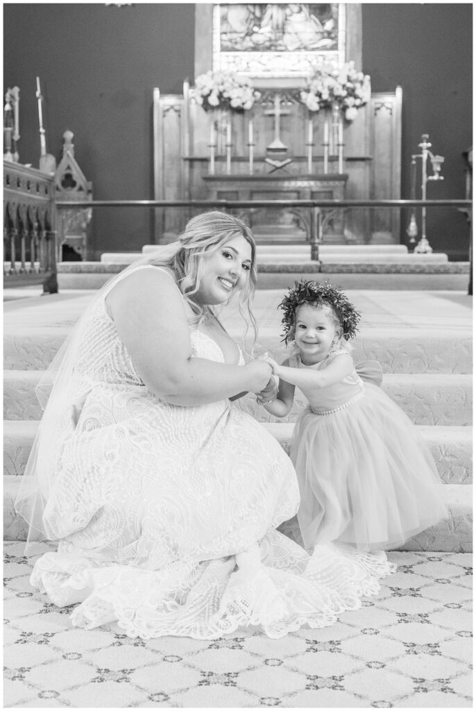 bride posing with the flower girl at the stairs of the altar in a church