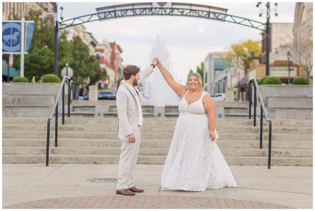 groom twirling the bride at the bottom of the stairs near Sandusky fountain