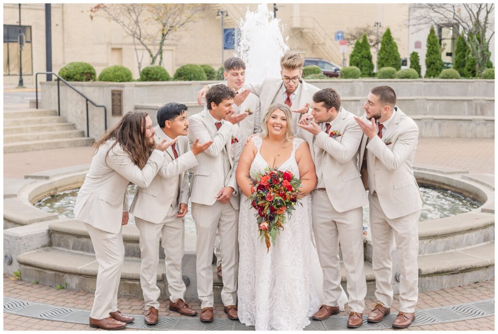 groomsmen blowing kisses to the bride while standing in front of the fountain