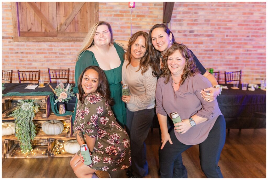 wedding guests posing together and holding drinks with the couple's koozies 