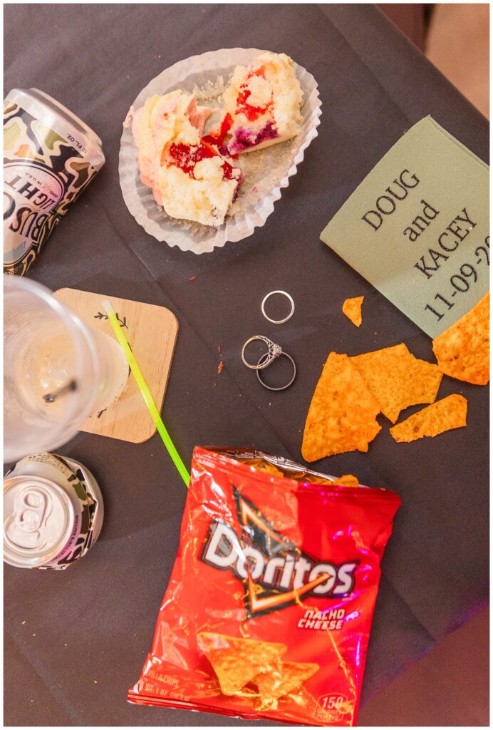 "trash the wedding" details from the wedding day including cake, glow stick, chips, beer can, and the bride and groom's rings