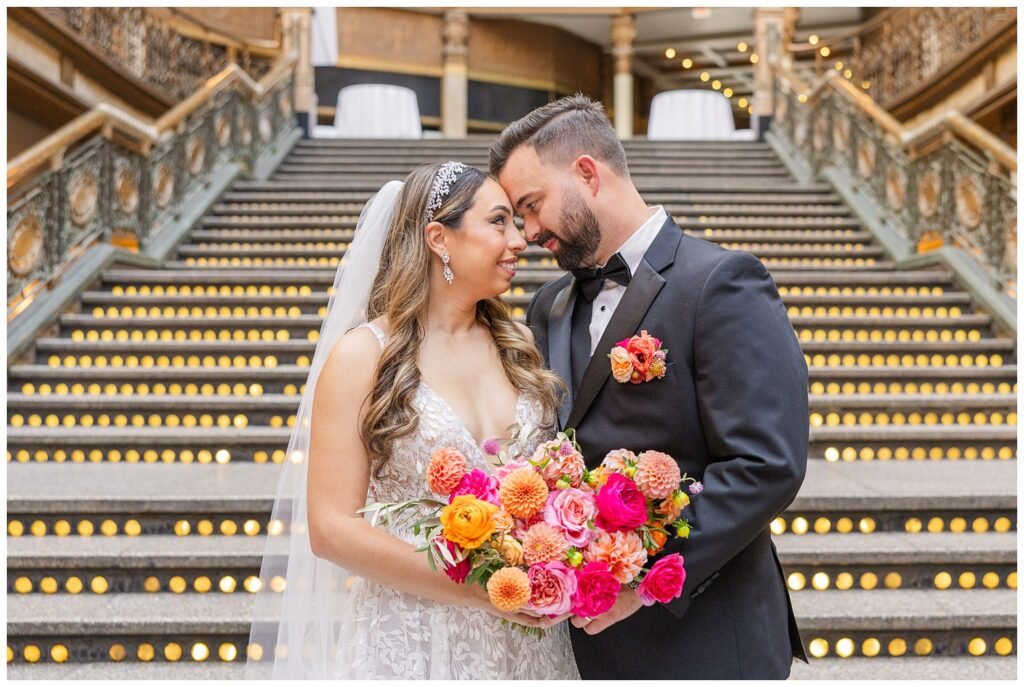 groom and bride posing with each other while holding bouquet in the middle