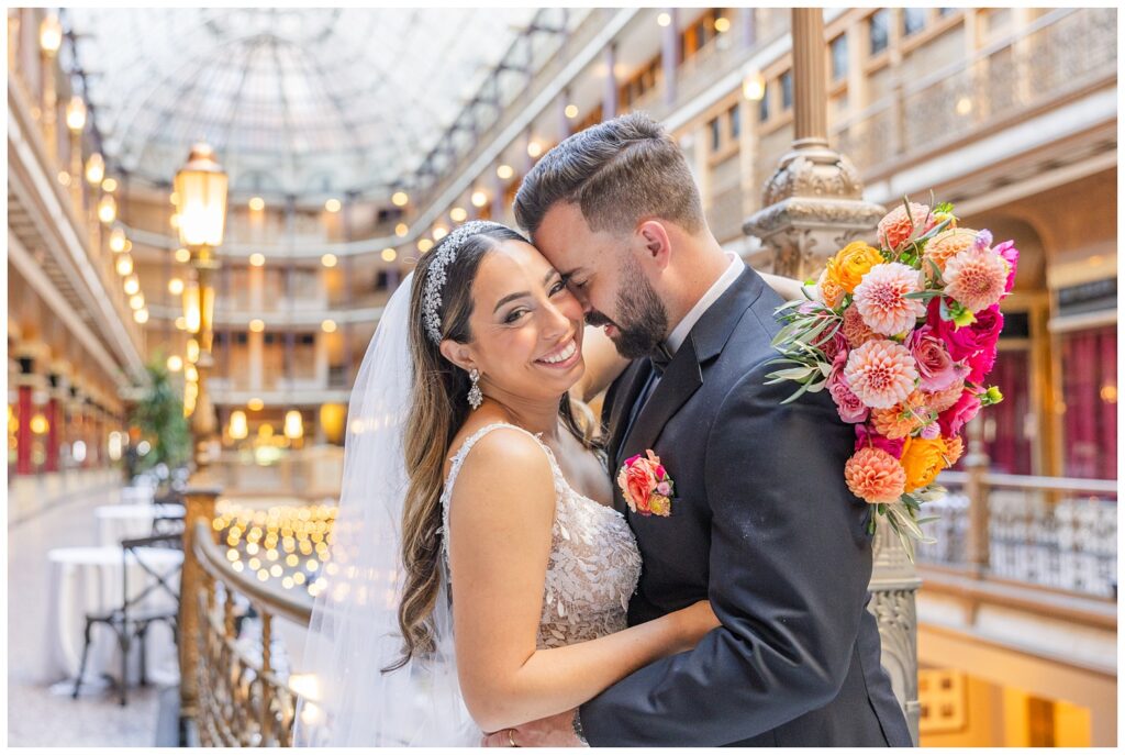 wedding couple hugging on the balcony with bouquet wrapped around groom's back