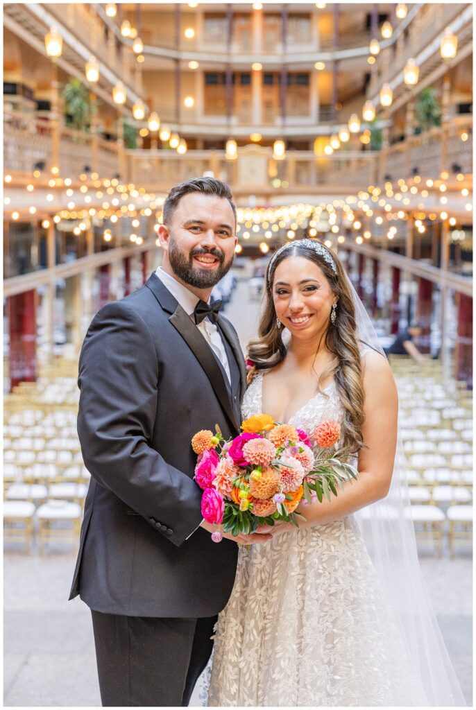 wedding couple posing together on the stairs with the ceremony chairs behind them