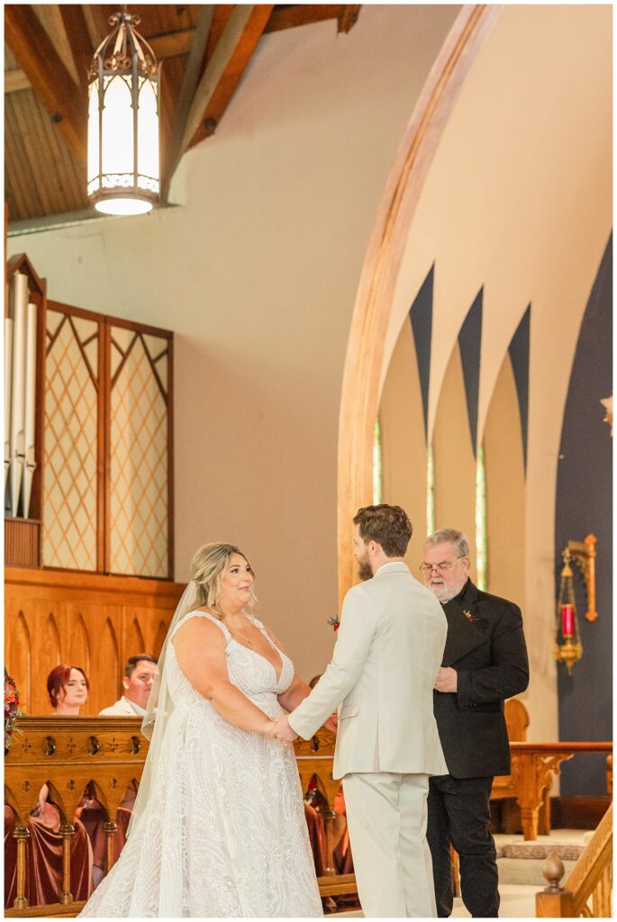 bride and groom holding hands and exchanging vows during fall wedding ceremony 