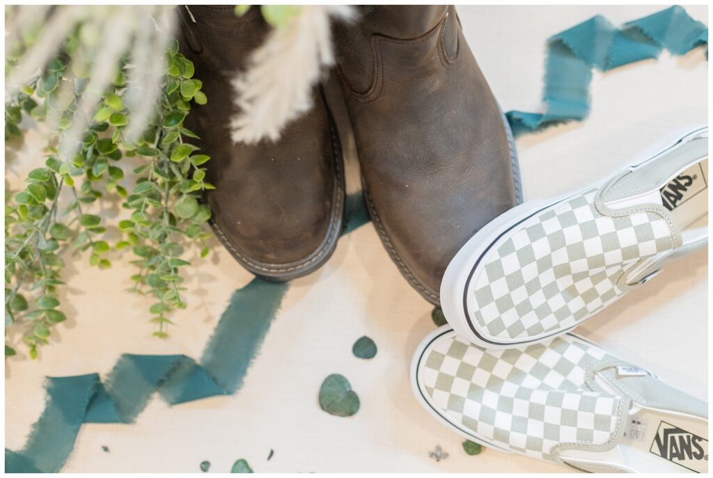 bride and groom's Vans and boots on a beige styling mat with dark blue ribbon