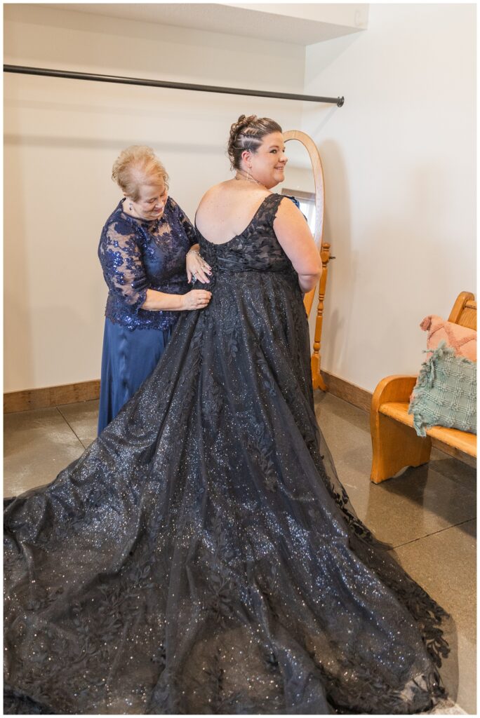 bride's mom zipping up the bride in her black lace wedding dress at Pickwick Place