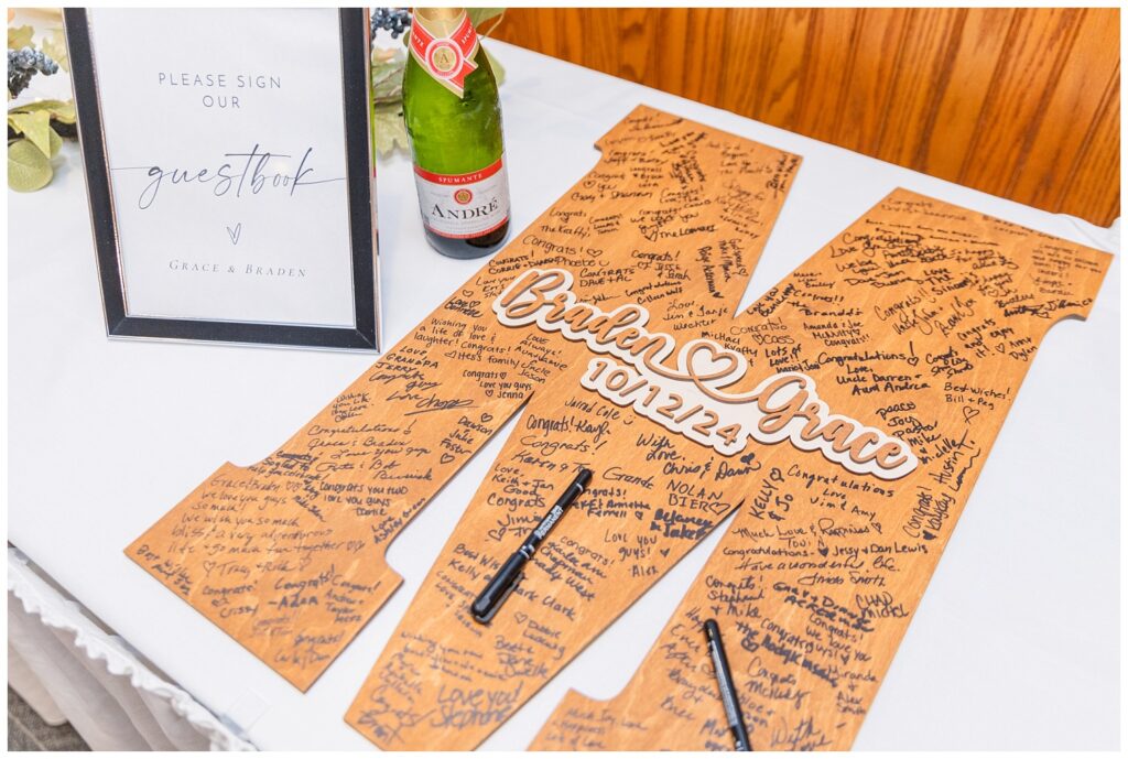 a large wooden M sitting on a reception table for the wedding guests to sign