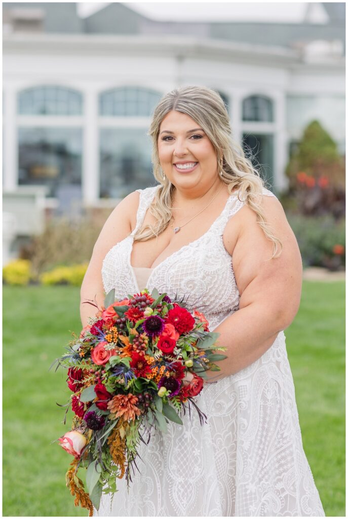 portrait of bride showing off her purple, pink, and red bouquet