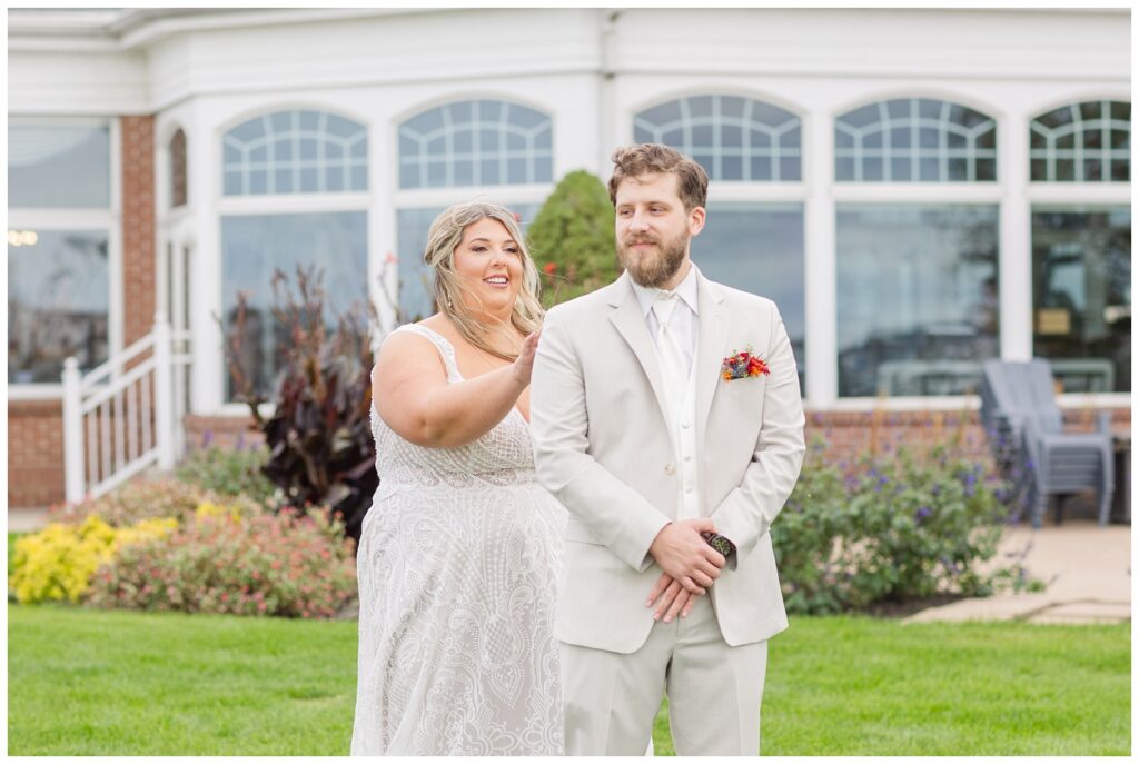 bride touching the groom on his shoulder during first look