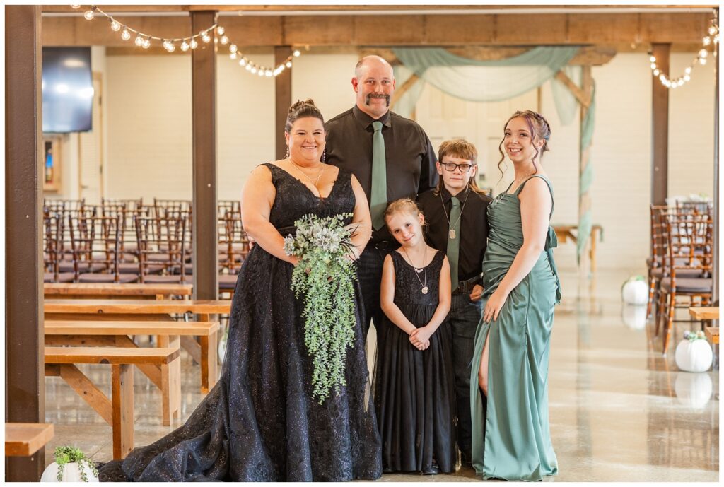 family portrait of the bride and groom with their children at the ceremony site