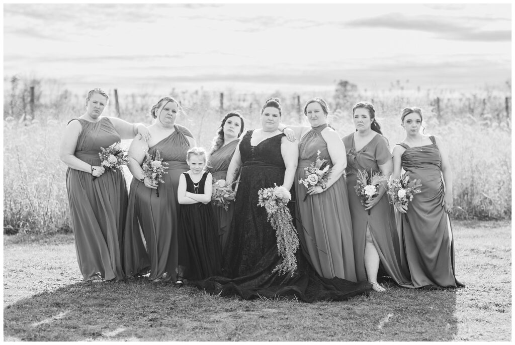 bridal party posing with serious looks outside in front of the field 