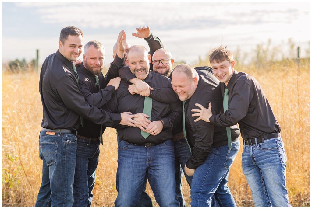 groomsmen all hugging around the groom outside at Pickwick Place wedding