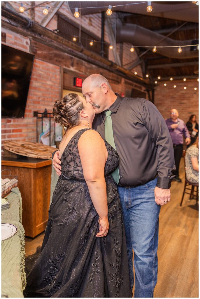 bride and groom share a kiss after cutting their cake inside the reception room at Pickwick Place