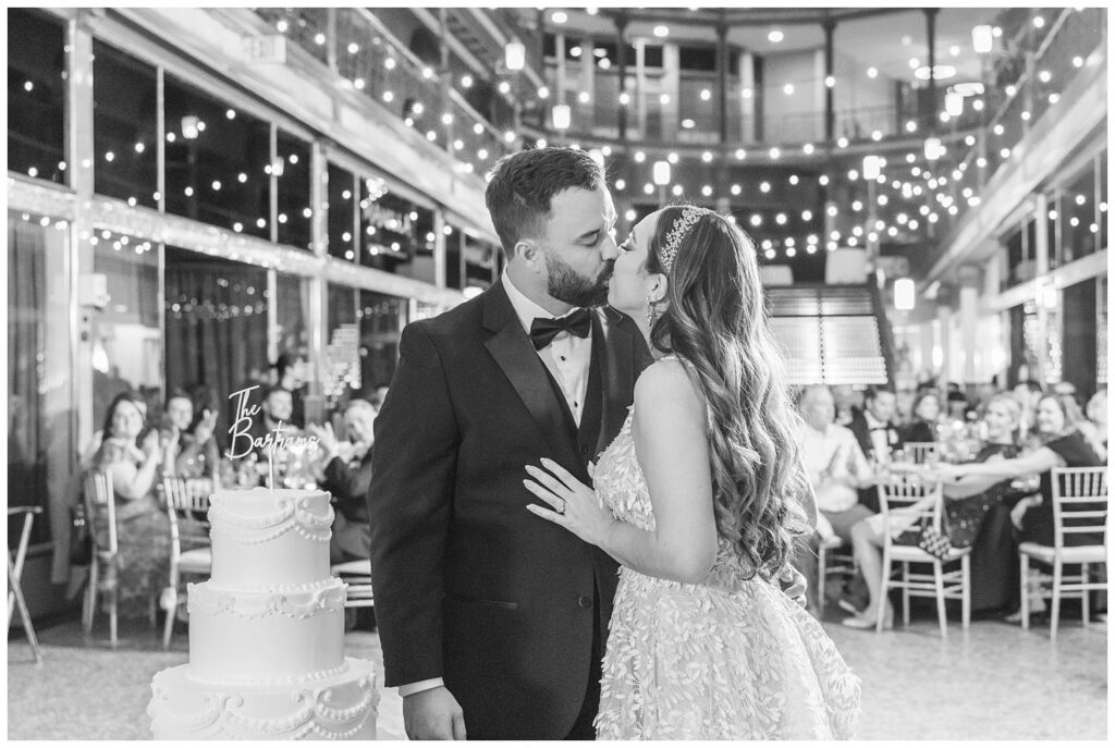 bride kissing groom after cutting their cake at the Arcade Cleveland