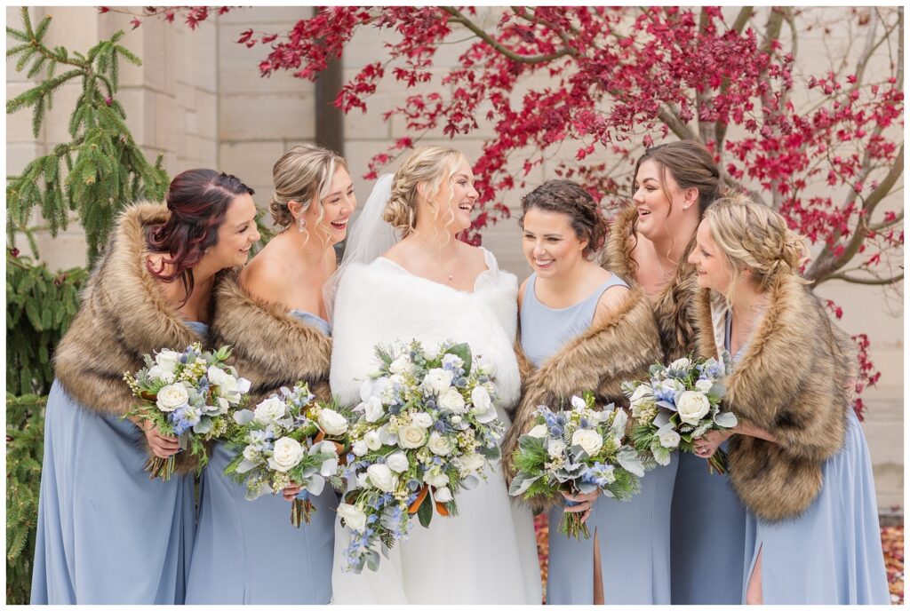 bridal party laughing together outside in front of a red tree at church