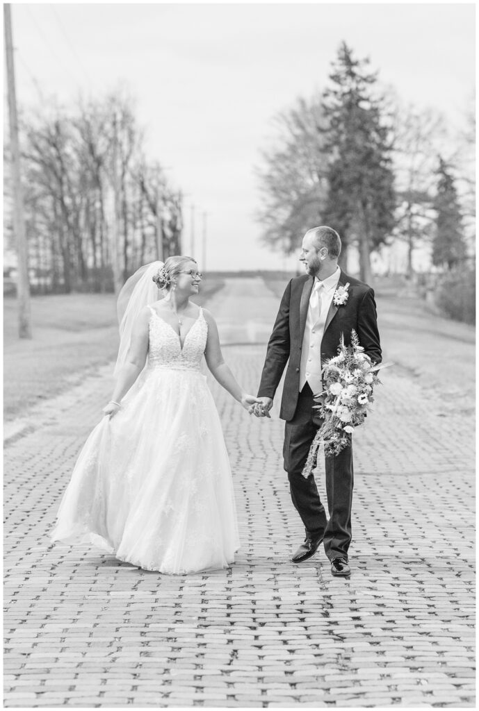 wedding couple holding hands and walking along a brick road near Monroeville, OH