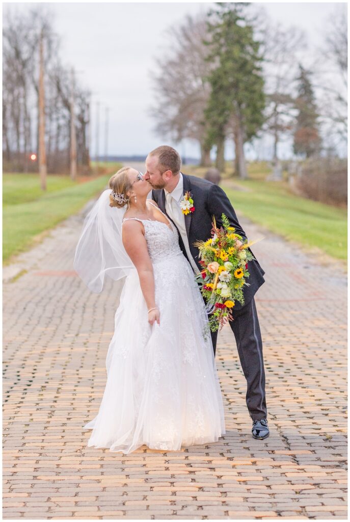 groom dipping the bride back for a kiss while holding her bouquet