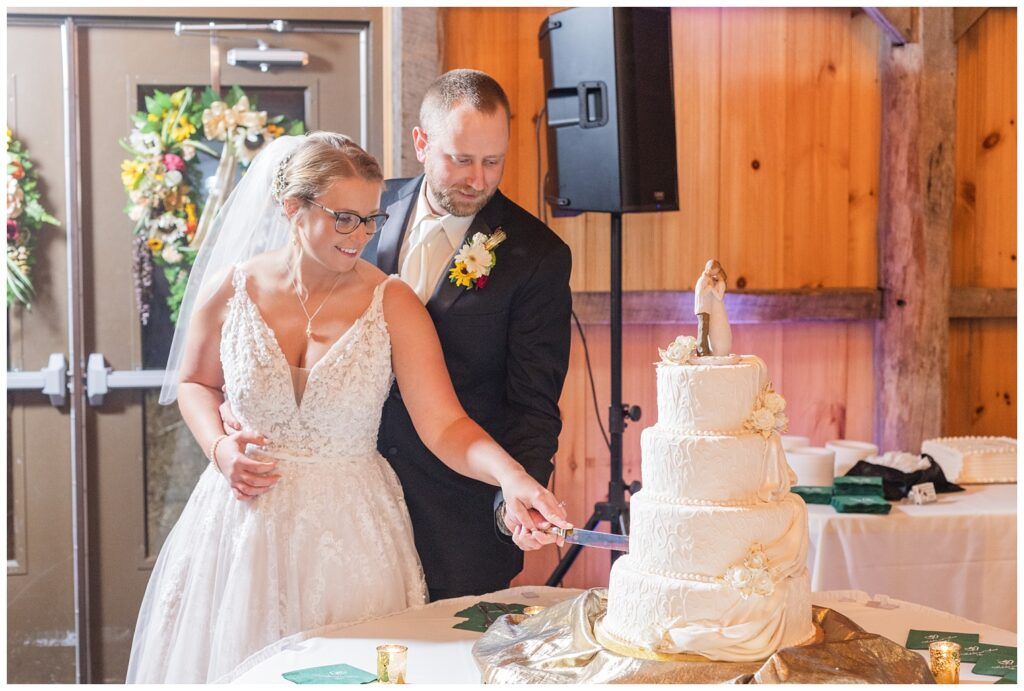 wedding couple cutting their cake at fall reception at the Village Barn