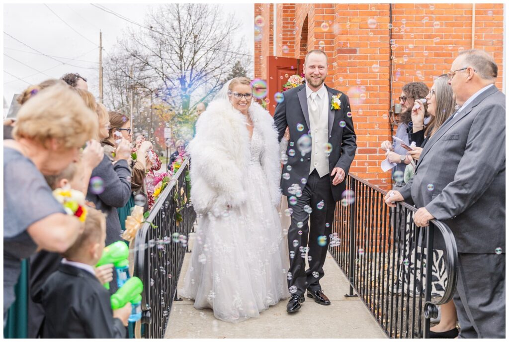 wedding couple walking out of the church to the wedding guests blowing bubbles