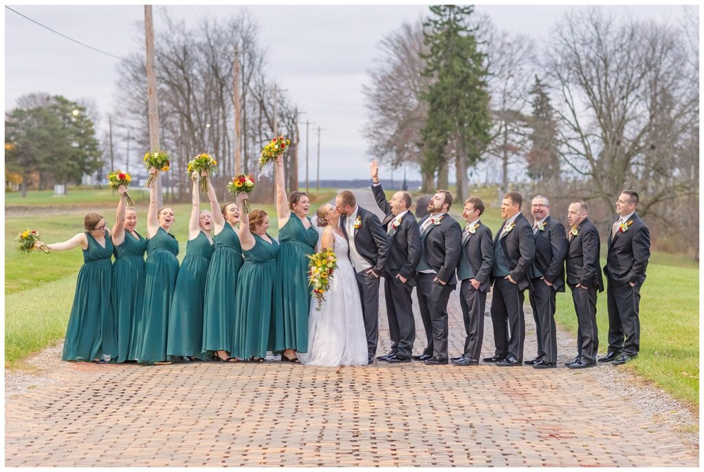 bride and groom kissing while the wedding party cheers them on