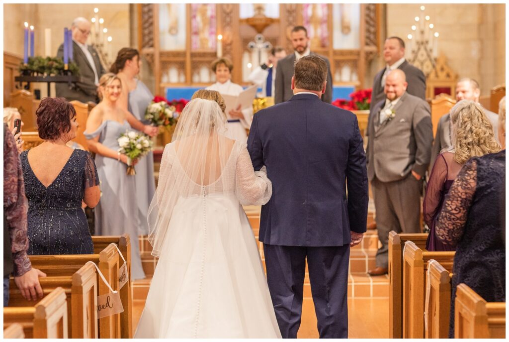 back of the bride and her dad as they are walking down the aisle at winter ceremony