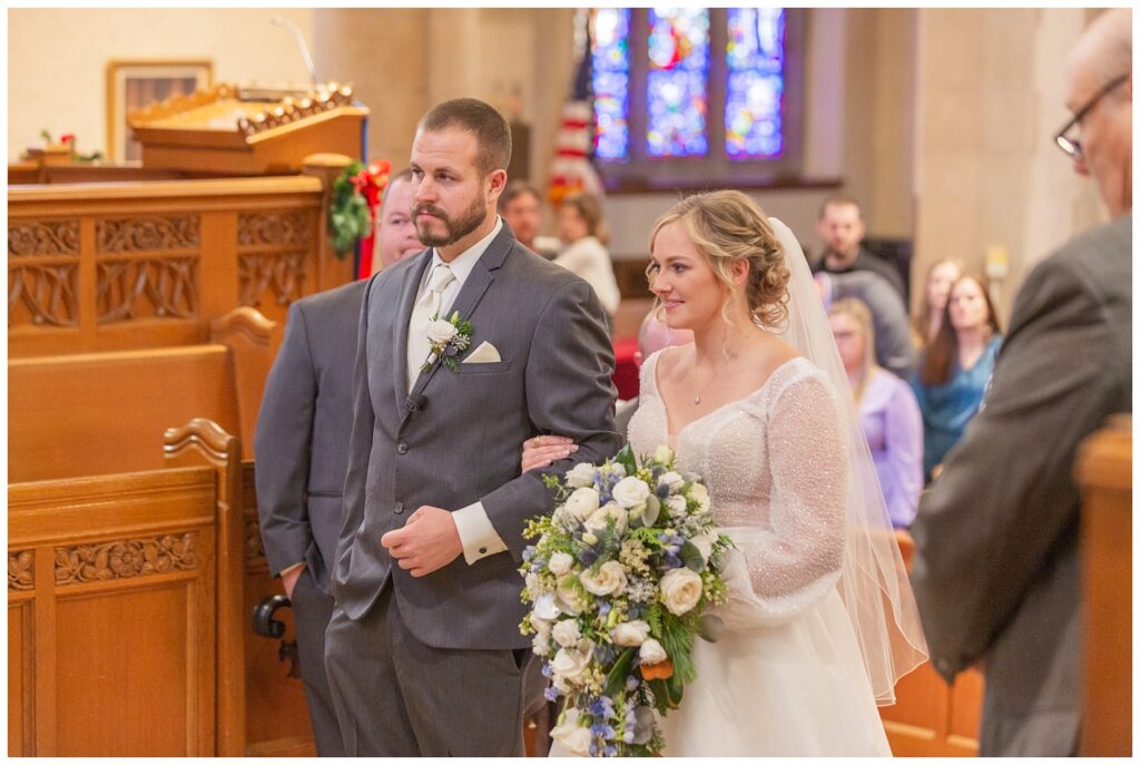 bride holding onto the groom's arm while standing together at the altar