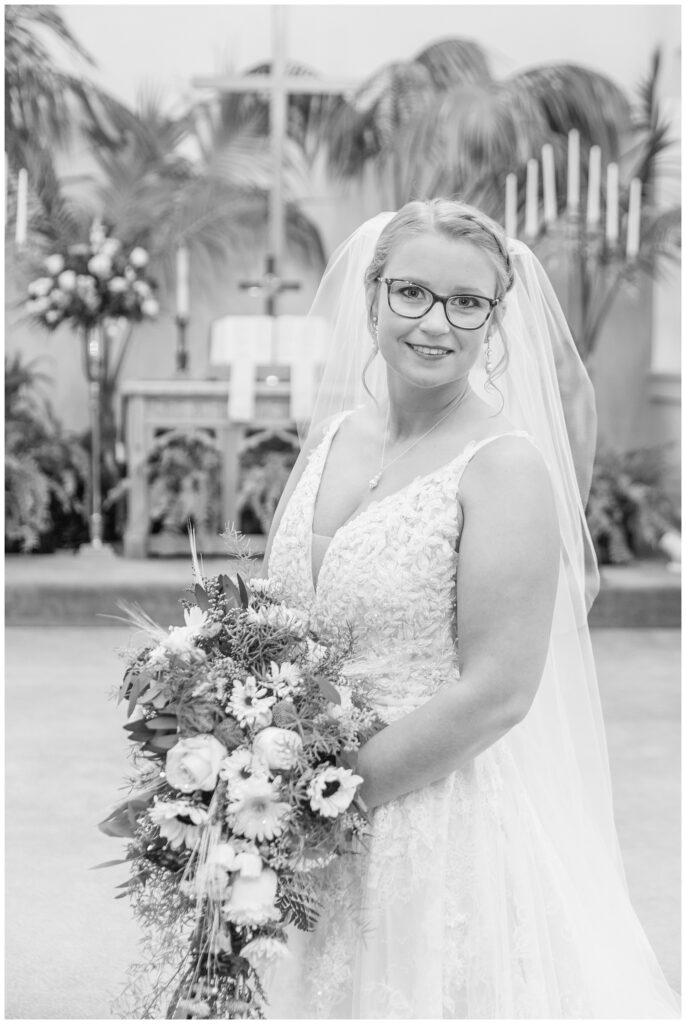 bride posing with her bouquet at the church altar before the ceremony