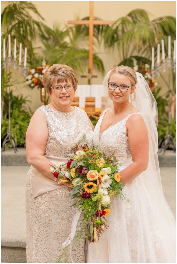 bride and her mom posing for portraits in front of the altar