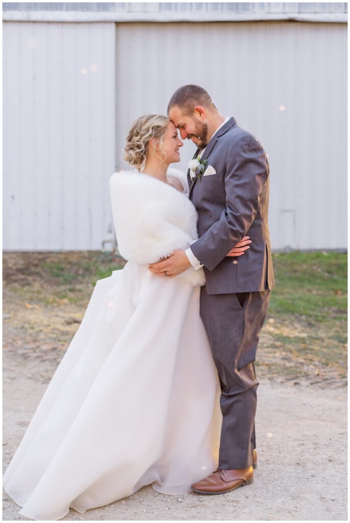 bride and groom holding each other outside during golden hour at farm