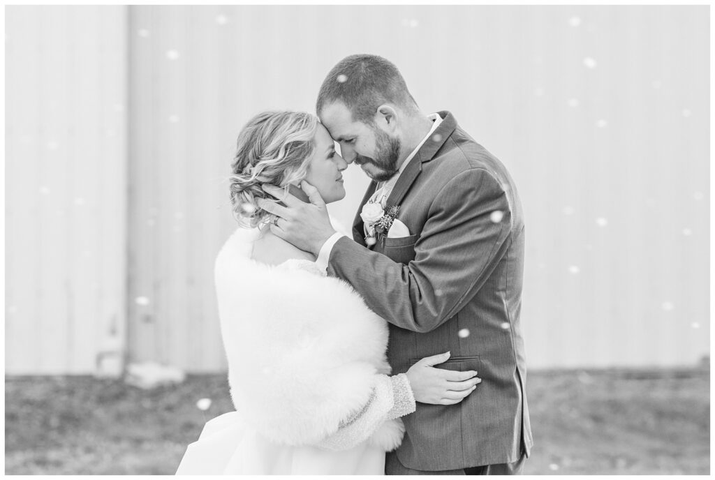 groom and bride touching foreheads while snow is falling in Fremont, Ohio