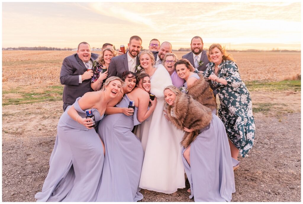 bride and groom posing with drinks with the wedding party on the groom's family barn