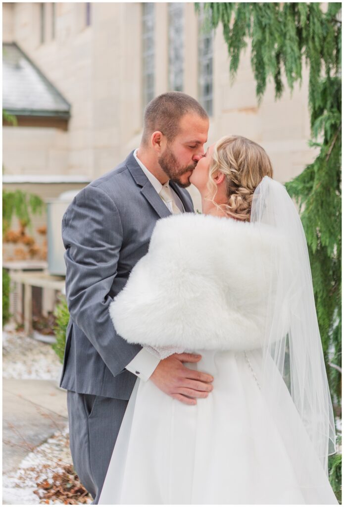 bride and groom share a kiss during their first look outside during winter wedding