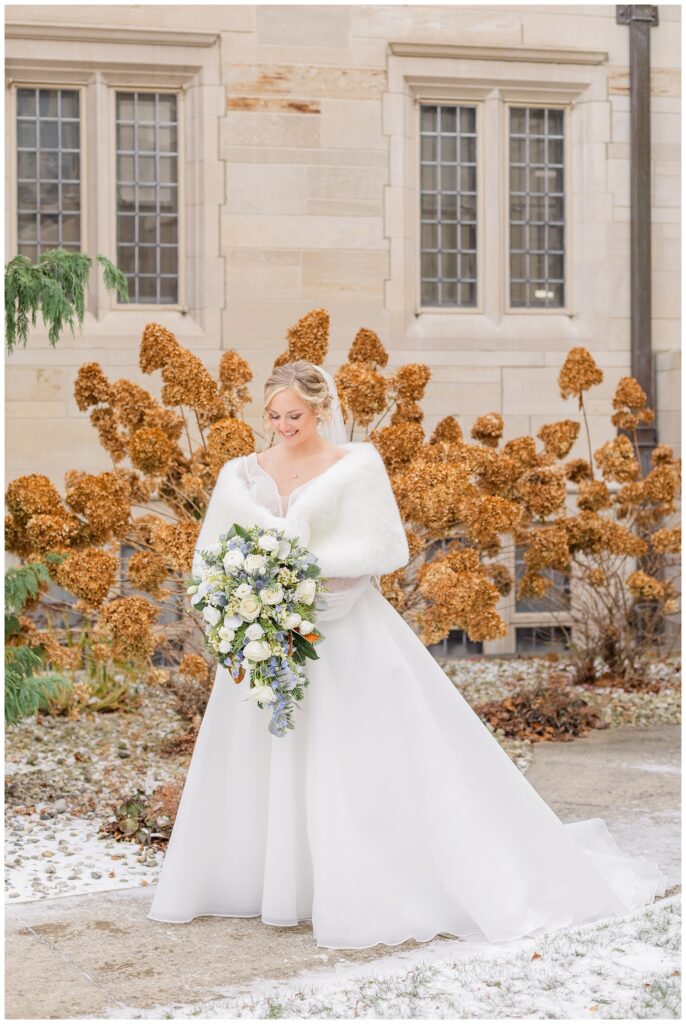 bride looking down at her blue and white bouquet at church ceremony