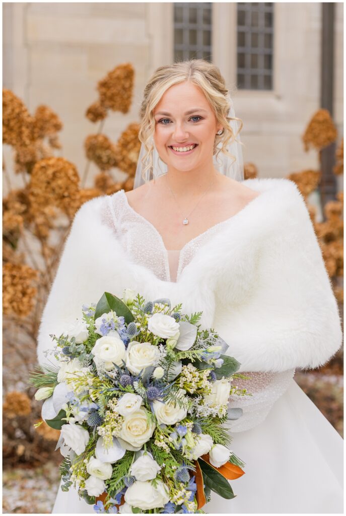 bride wearing a white shawl and holding her wedding bouquet outside the church 