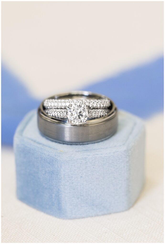 wedding rings sitting on top of a blue ring box top with blue ribbon