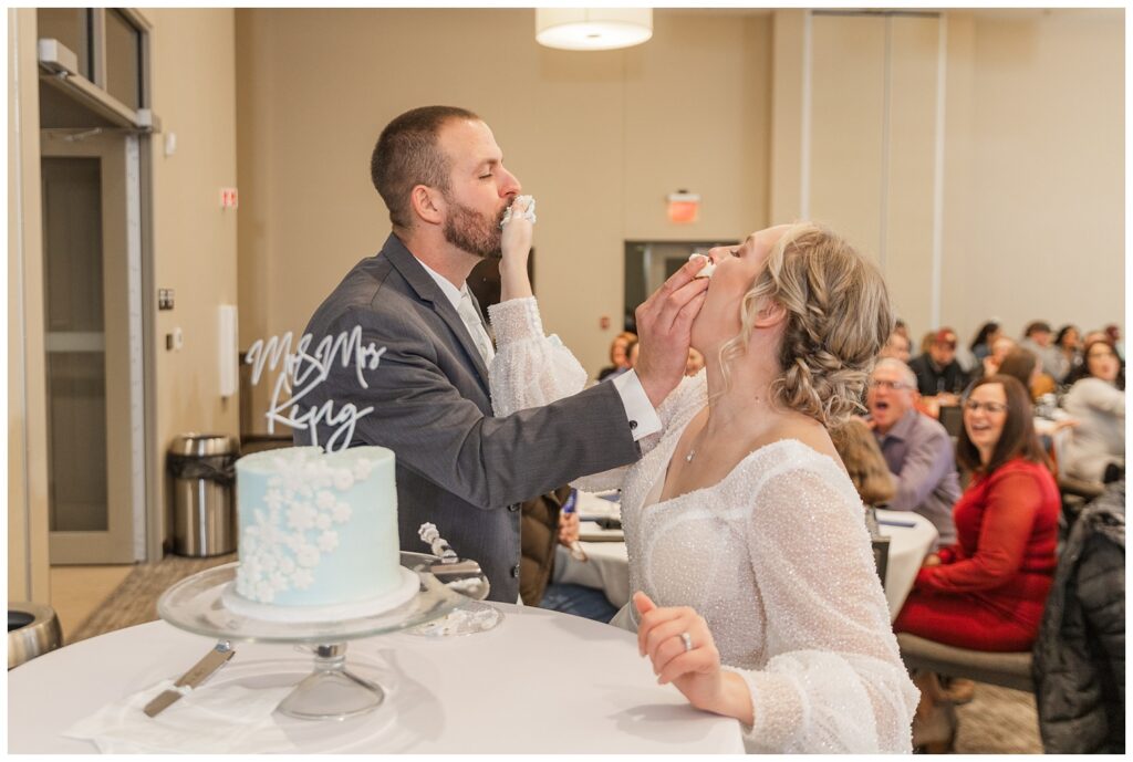 wedding couple smashing cake in each other's faces at the Neeley Center