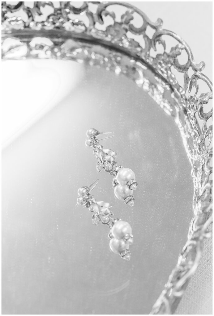 bride's pearl earrings sitting on a glass silver tray 