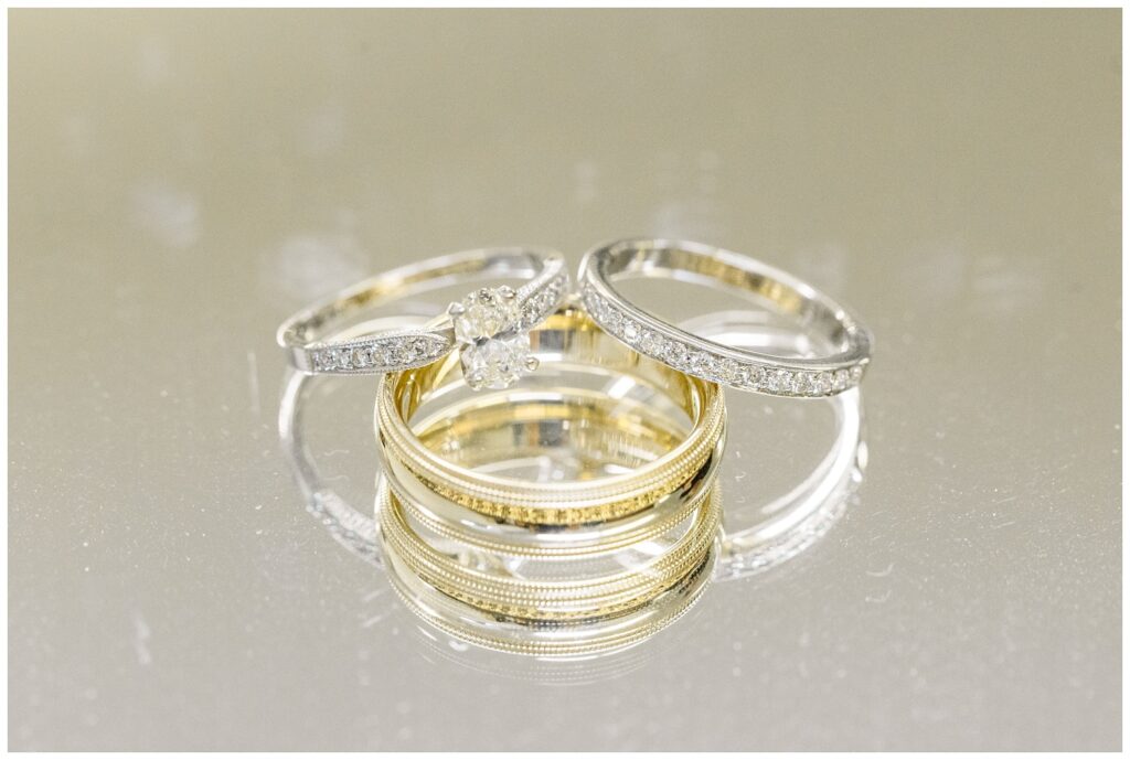 bride and groom's wedding rings stacked on each other on a glass tray