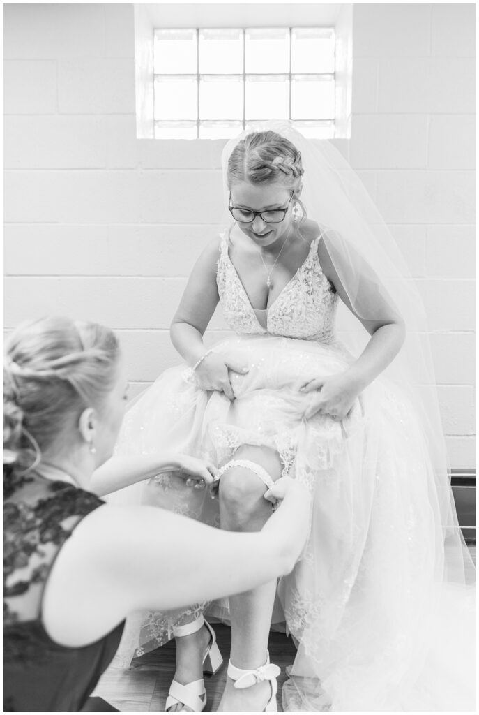 bridesmaid adjusting the bride's garter while getting ready for the wedding ceremony