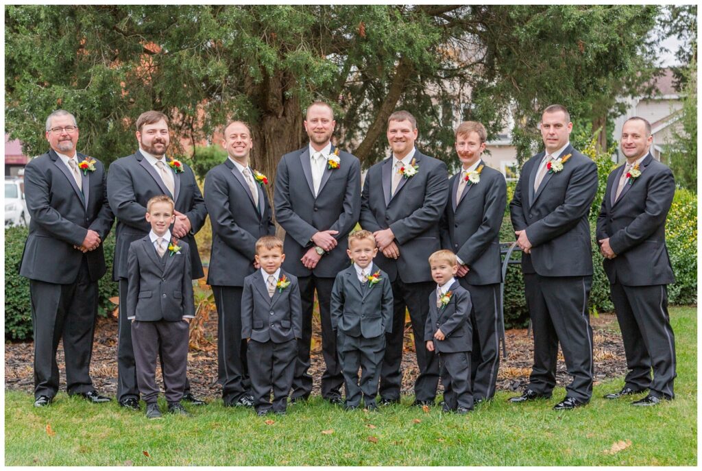 groomsmen posing outside in front of a tree at the church near Monroeville, OH