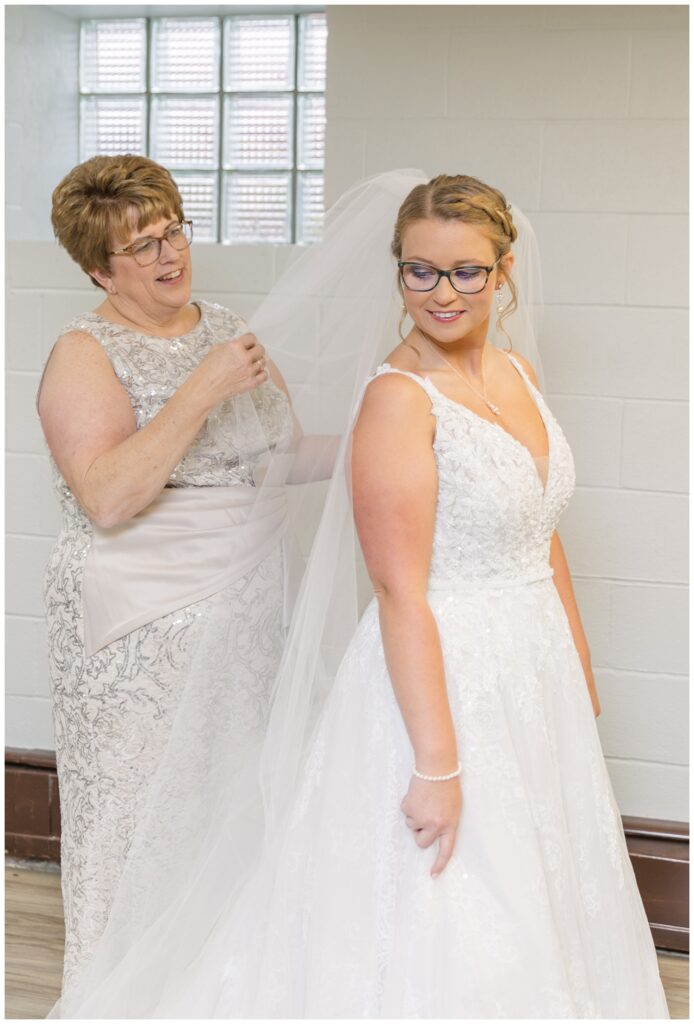 bride's mom adjusting her veil in the church basement before the ceremony