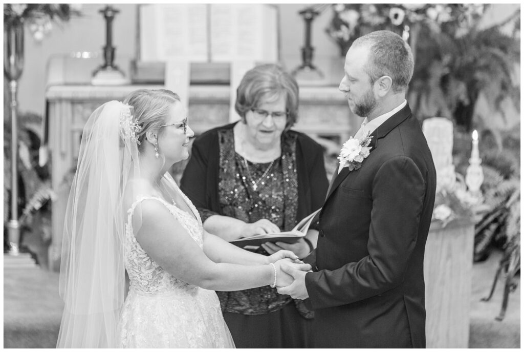 bride and groom holding hands and saying their vows during church ceremony