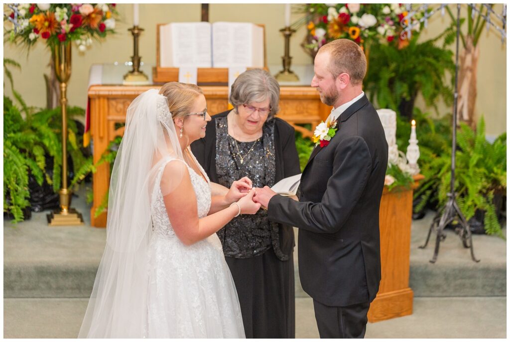 bride placing the wedding ring on groom's hand during Monroeville, OH ceremony