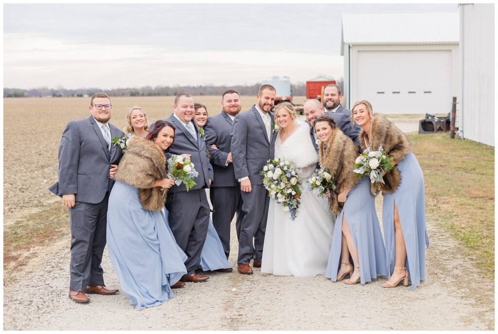 wedding party posing behind a white barn on the bride's family farm