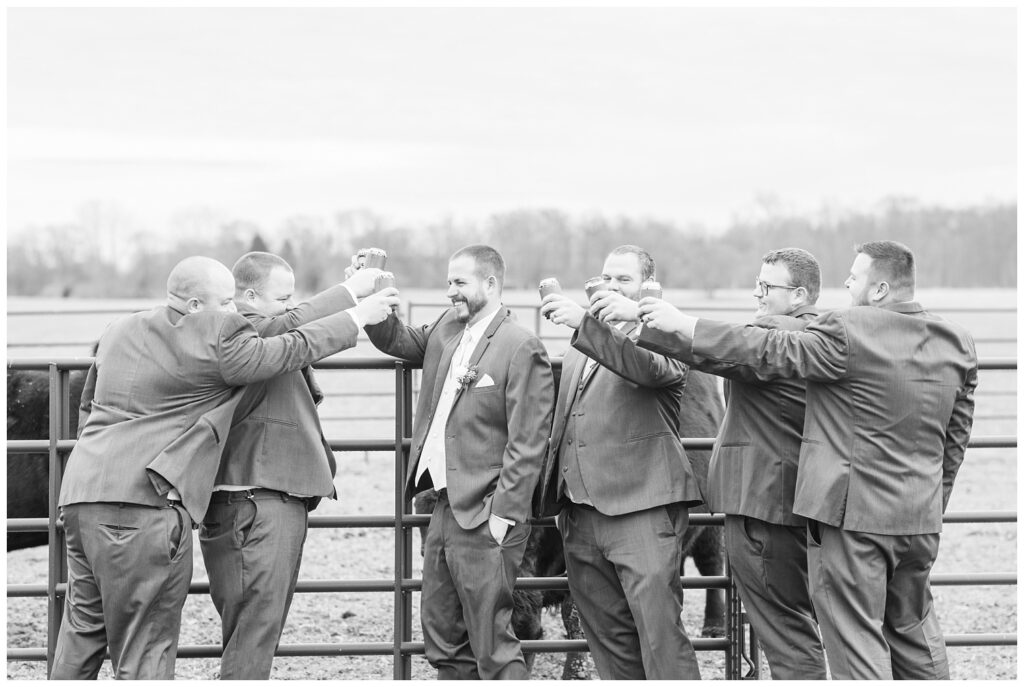 groomsmen toasting with beers while posing on the bride's family farm