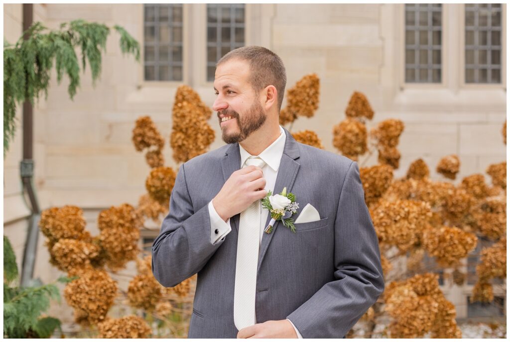 groom adjusting his white tie outside in the church courtyard in Fremont, Ohio