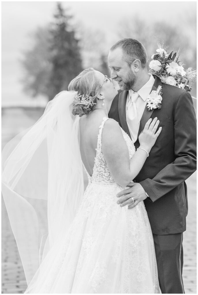 bride and groom smiling at one another on a brick road with the bouquet behind the groom's head