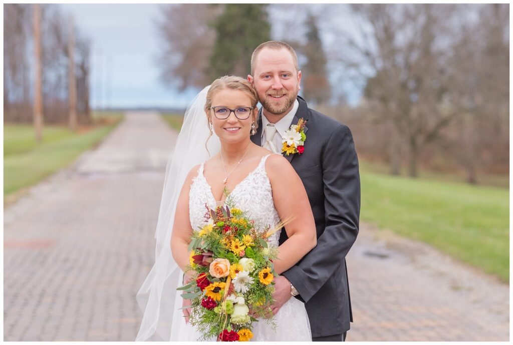 groom posing behind the bride while she holds her bouquet 