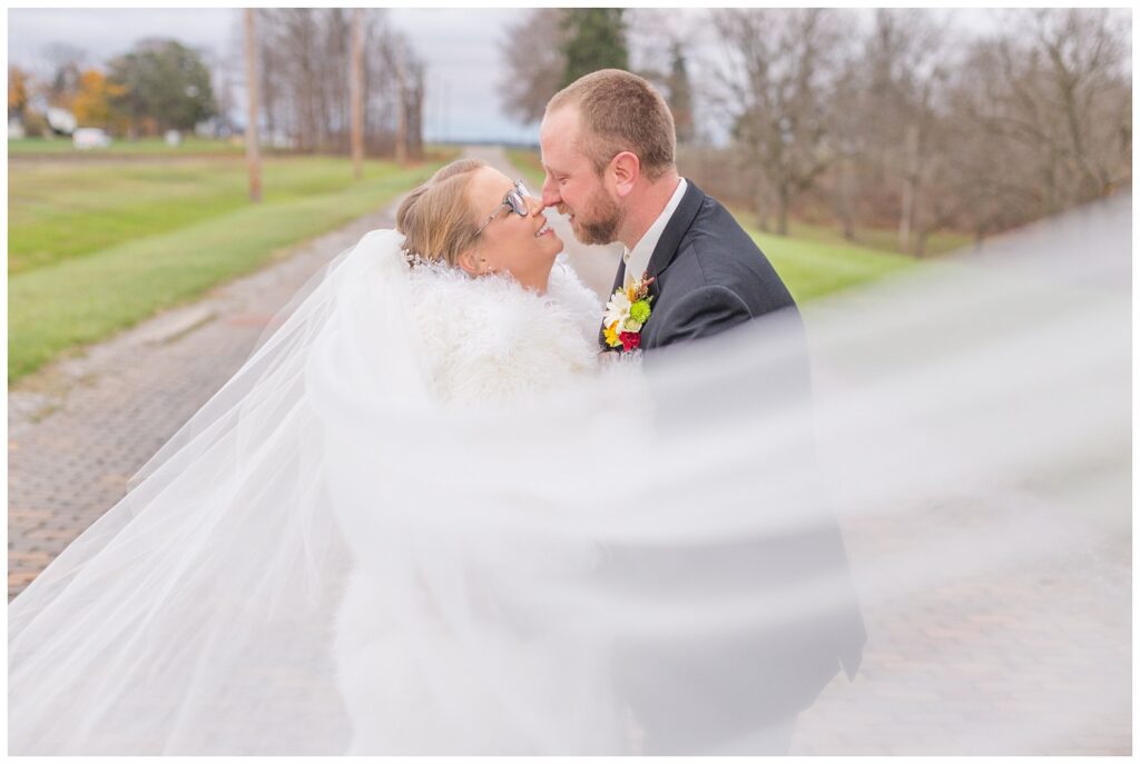 bride's veil wrapped around the wedding couple on a brick road in Ohio